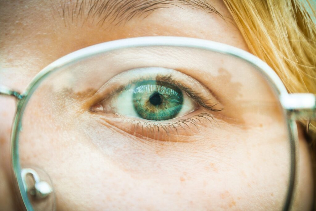 Close up of woman's blue eye through glasses lens