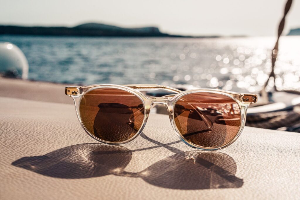 Brown lens sunglasses on the side of a boat with the sea in the background