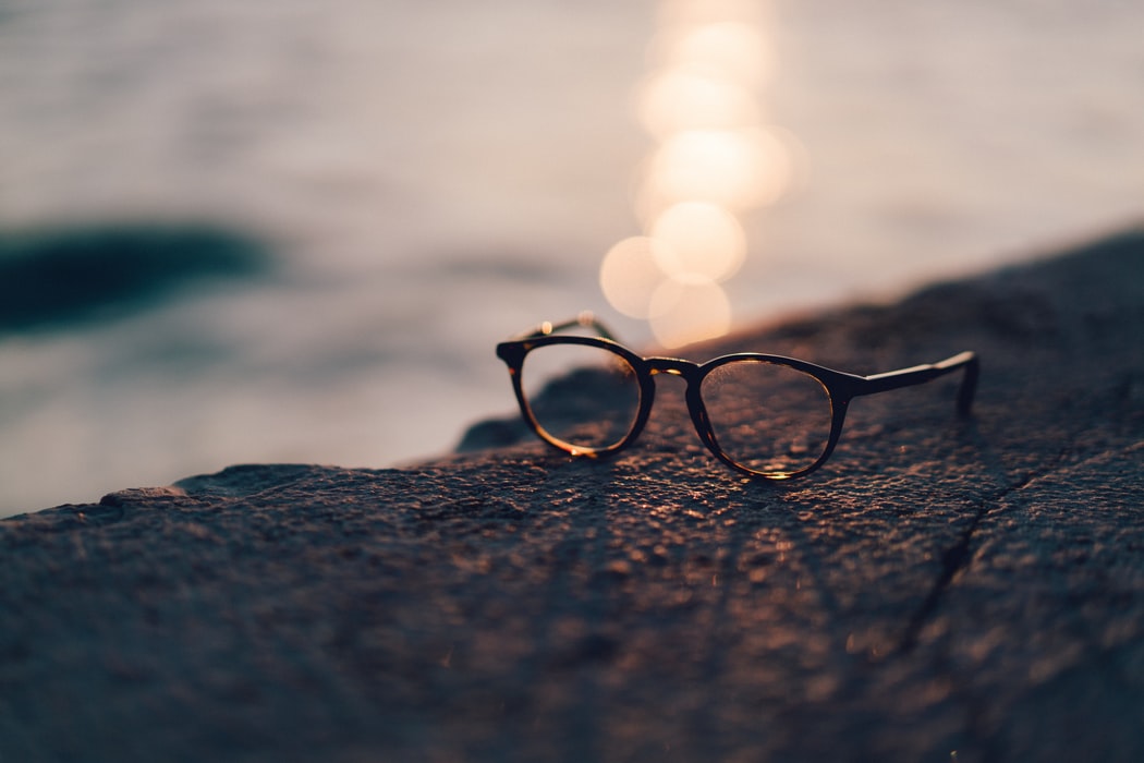 Glasses frames on a rock with the sunset behind them