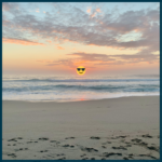 Cornish beach at sunset with footprints along the sand and a sunglasses emoji covering the sun