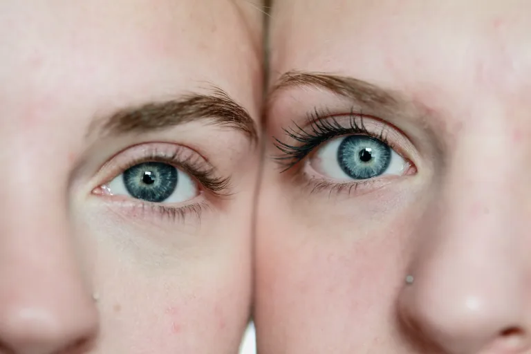 Close up of two women with their heads side by side, looking into the camera with blue eyes