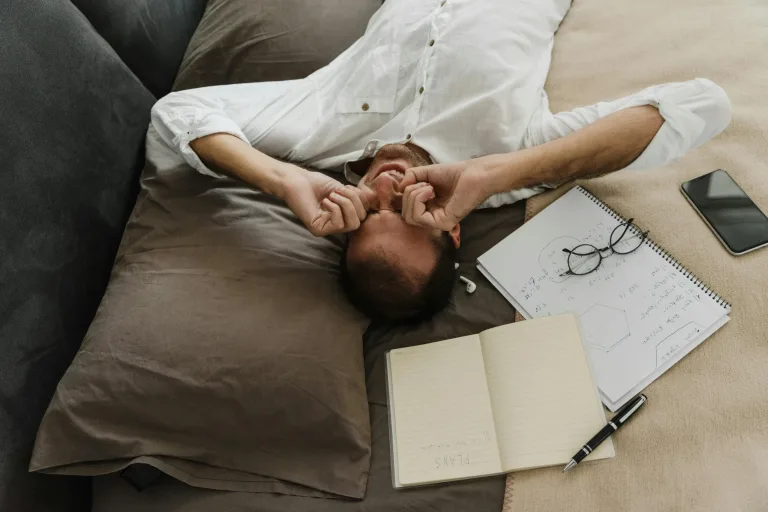 man lying down rubbing his eyes